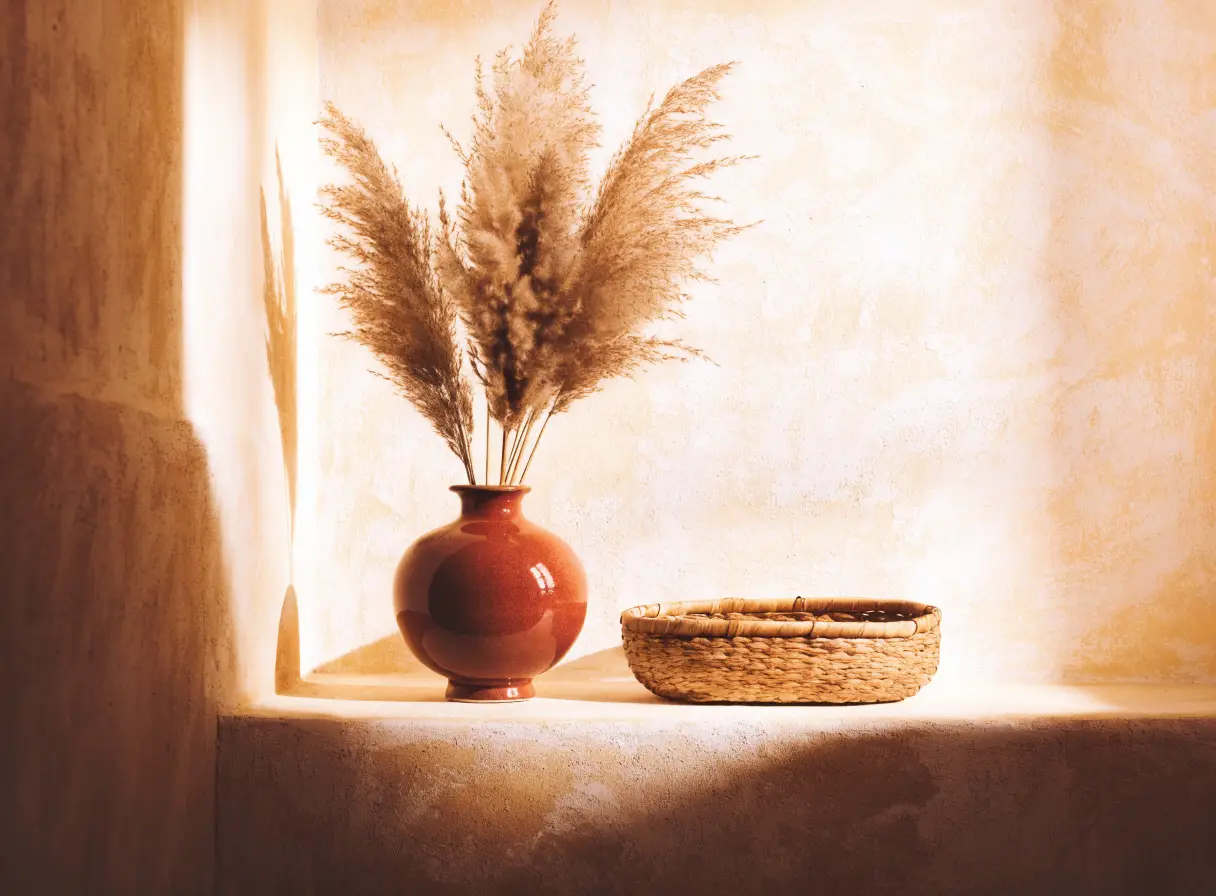 A ceramic vase, dried grasses and a woven basket